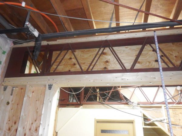 ラチス梁の下に木造の耐力壁を設置するため木製の梁をラチス梁にボルト接合し、その上で柱とラチス梁を包むように合板を張りました。